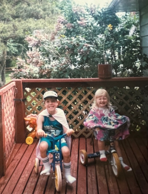 My sister and I riding our tricycles on a deck